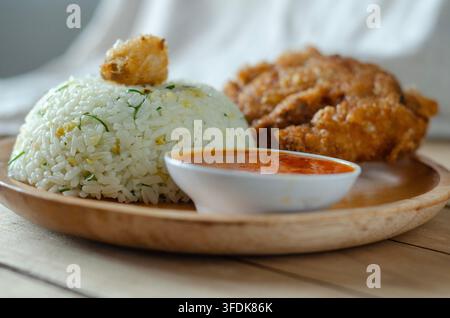 Knuspriges gebratenes Hähnchen serviert mit duftendem Reis und Chilisauce Stockfoto