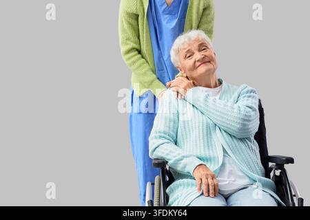 Altenpflege und Pflegeunterstützung, Betreuerin mit einer älteren Frau im Rollstuhl, die Trost und Mitgefühl in einer medizinischen oder betreuten Wohnanlage bietet Stockfoto