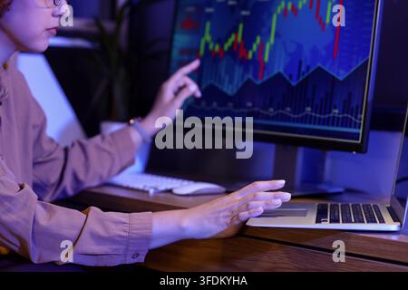 Finanzmarktanalyse und Aktienhandel, Frau überwacht Investitionsdaten und Kryptowährungsdiagramme auf Computerbildschirmen während der Spätarbeit Stockfoto