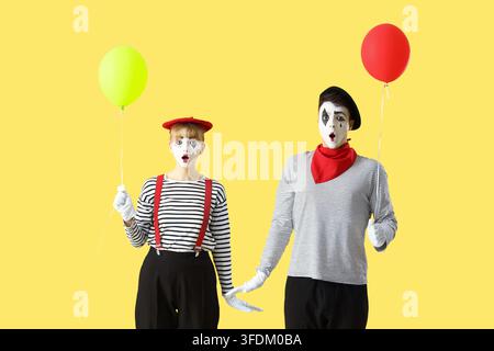 Ein paar Pantomimisten mit Ballons auf gelbem Hintergrund Stockfoto