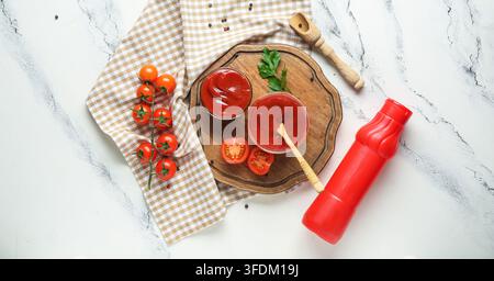 Gesunde Ernährung und Bio-Lebensmittel, frischer Tomatenketchup in Glasschalen mit rohen Tomaten und Holzläffel auf einem rustikalen Küchentischhintergrund Stockfoto