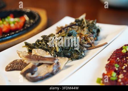 Verschiedene koreanische traditionell gewürzte Gemüse und Pilze Banchan, elegant auf einem Teller serviert, gesunde vegane Beilagen Stockfoto