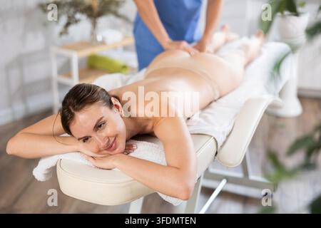 Die abgeschnittene junge Männerhand schrubbt während des allgemeinen Massageverfahrens aktiv das Bein der Frau. Nahaufnahme Stockfoto