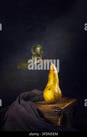Ländliche Stillleben, Low-Key-Fotografie - Blick auf eine einsame Birne auf einer Holztruhe, Nahaufnahme mit selektiver Schärfe Stockfoto