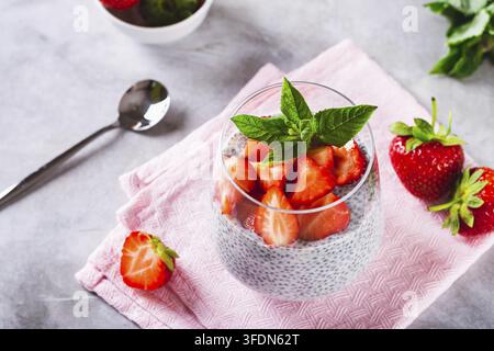 Frische Chiasamen mit Milch, frischen Erdbeeren und Minze in einem Glas auf dem Tisch Stockfoto