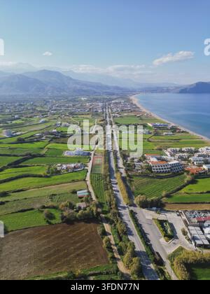 Helle grüne Felder am Meer auf Kreta im Winter auf der sonnigen griechischen Insel, ländliche landwirtschaftliche Landschaft kombiniert mit mediterraner Küste und klarem Stockfoto