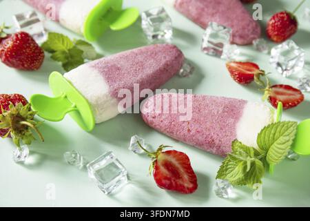 Erfrischende hausgemachte Erdbeer-Eiscreme oder Eis am Stiel auf weichem grünem Hintergrund Stockfoto