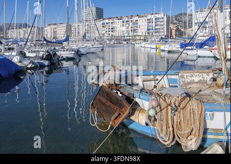 Nahaufnahme des Hecks eines Fischerboots mit aufgehängten Netzen im Hafenbecken vor Segelbooten und den Wohnblöcken am Quai Cronstadt unter Stockfoto