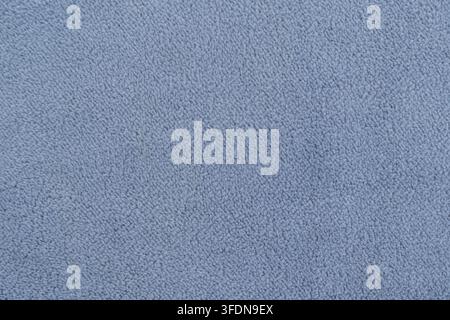 Nahaufnahme von weichem marineblauem Fleece-Stoff mit sanften Wellen. Die dicke, plüschige Textur erzeugt natürliche Highlights und Schatten und bietet eine gemütliche und warme Atmosphäre Stockfoto