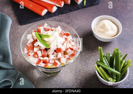 Hausgemachte Salataus Krabbenstangen, Eiern, Schnittlauch und Mais in einer Schüssel auf dem Tisch Stockfoto