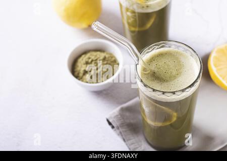 Eisgekühlte Matcha-Limonade mit Zitrone in Gläsern mit Strohhalmen auf dem Tisch Stockfoto