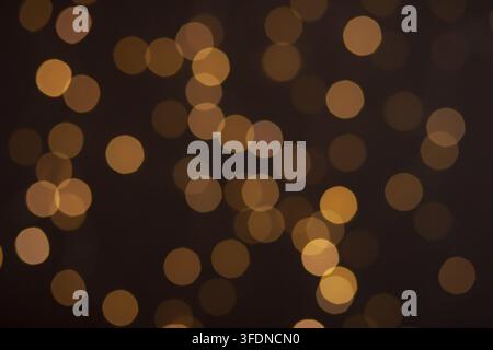 Weihnachtslichter im Bokeh. Gelbe und feuerorange Bokeh auf schwarzem Hintergrund, abstraktes Bokeh-Hintergrund Stockfoto