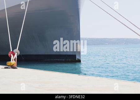 Anlegen eines Schiffes im Hafen mit Hilfe von Festmacherleinen an einem Poller am Kai. Foto in guter Qualität Stockfoto