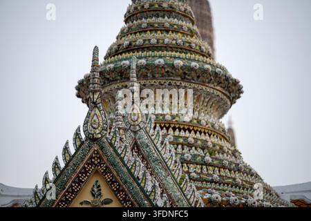 BANGKOK, THAILAND — 31. JANUAR 2026: Ein verzierter Tempeldachgiebel steht vor dem mit Keramik verzierten Prang des Wat Arun in Bangkok Yai. Stockfoto