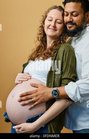 Schwangeres Paar umarmt mit Zärtlichkeit und Vorfreude den Babybauch im Mutterschaftsporträt Stockfoto