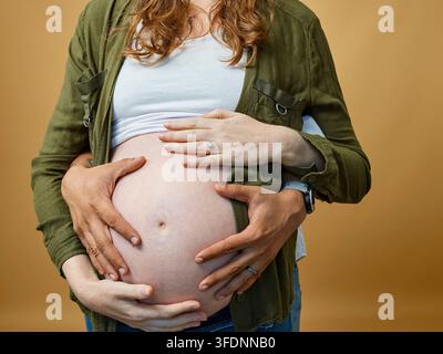Schwangere Paare umarmen den Babybauch im Nahaufnahme, Mutterschaftliche Liebe, Vorfreude und Zusammengehörigkeit Stockfoto
