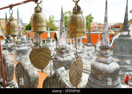 Nahaufnahme von traditionellen Tempelglocken mit verschwommenen kleinen Stupas im Hintergrund im Wat Phra Mahathat, einem UNESCO-Weltkulturerbe in Nakhon Si Thammarat Stockfoto