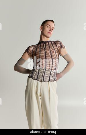 Eine junge queere nicht-binäre Person präsentiert einen einzigartigen Stil in einem schicken Outfit. Stockfoto