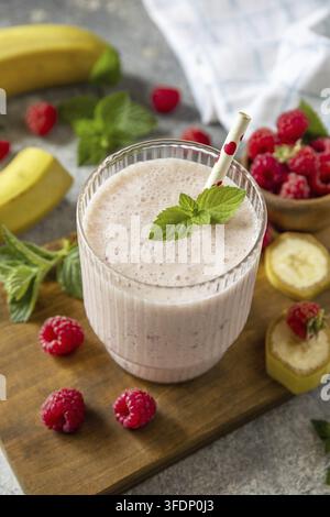 Rosa Himbeeren und Bananen-Fruchtsmoothie oder Milchproteinshake auf steinerner Tischplatte. Joghurt-Cocktail, natürliche Detox-Kur. Flüssiges Eis Stockfoto