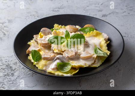 Deliziöse italienische Ravioli-Pasta mit cremiger Pilzsauce und frischem Basilikum Stockfoto