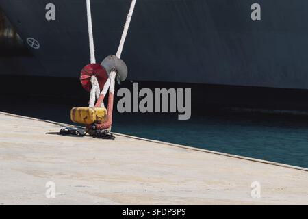 Anlegen eines Schiffes im Hafen mit Hilfe von Festmacherleinen an einem Poller am Kai. Foto in guter Qualität Stockfoto