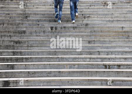 Zwei Paar Beine, die eine Steintreppe hinaufsteigen Stockfoto