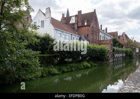 Ruhiger Kanal, gesäumt von historischen Backstein- und weißen Häusern mit üppigen grünen Gärten und Bäumen im mittelalterlichen historischen Zentrum der Stadt. Brügge, Belgien Stockfoto