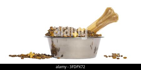 Hundefutternapf voller Trockenfutter und ein Kauknöchelchen, mit verschütteten Keksen Stockfoto