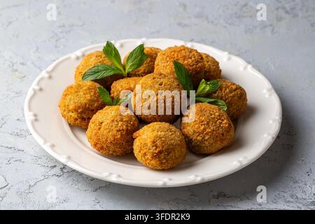 Knusprige goldbraun gebratene Falafel-Kugeln, serviert auf einem weiß gemusterten Teller Stockfoto
