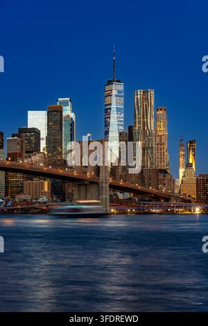 Prachtvolle Aussicht auf die Skyline von Downtown Manhattan bei Sonnenaufgang, die die beleuchtete Brooklyn Bridge und die Wolkenkratzer des Finanzdistrikts zeigt Stockfoto