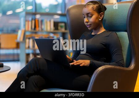 Student, der einen Laptop in der Bibliothek verwendet Stockfoto