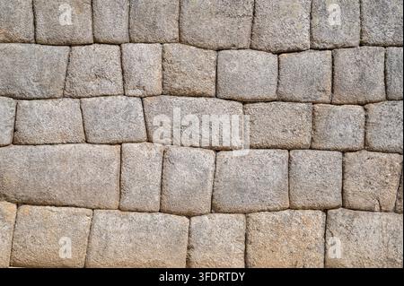 Alte Inka-Steinmauer in Cusco, Peru, mit präziser polygonaler Mauerarbeit, engen Fugen und rauer Granittextur. Ein historisches architektonisches Detail co Stockfoto