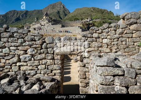 Alte Inka-Steinmauern und Terrassen in Machu Picchu, eingerahmt von schroffen Anden-Gipfeln, die historische Mauerarbeit, Tourismuswege und kulturelles Erbe zeigen Stockfoto