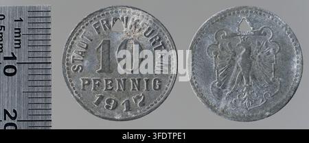 Zwei Münzen aus der Zeit des Ersten Weltkriegs aus Frankfurt am Main, Deutschland, darunter eine 10-Pfennig-Münze von 1917, hergestellt von Jörgum & Trefz, wobei eine Münze einen numerischen Wert und die andere eine Figur mit Krone und Flügeln zeigt. Stockfoto