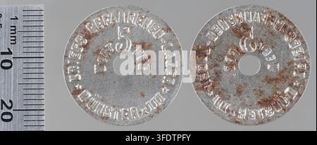 Zwei Kriegsmünzen aus der Zeit des Ersten Weltkriegs aus Münster, Deutschland, jede mit erhabener Schrift und einer zentralen Zahl, neben einem Metalllineal zur Größenbestimmung ausgestellt, hergestellt von Berg & Nolte, Lüdenscheid. Stockfoto