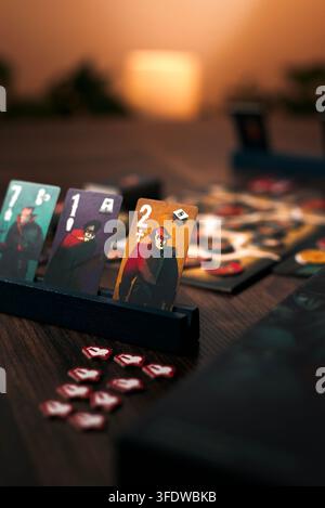 Atmosphärische Produktfotografie, die Brettspielkarten zeigt, die auf einer hölzernen Ablagefläche während eines wettbewerbsorientierten Duellspiels angeordnet sind. Unscharfes Spielbrett Stockfoto
