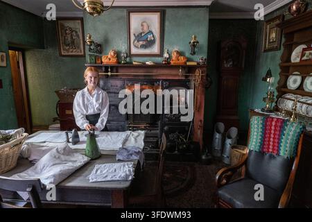 Junge Hausangestellte mit Bügeleisen Stockfoto