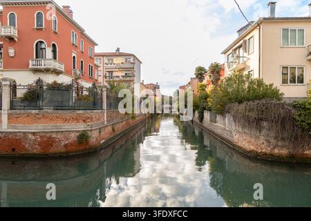 Ein ruhiger Wohnkanal mit farbenfrohen venezianischen Gebäuden und Wolkenreflexionen im Wasser, Lido di Venezia, Venedig, Italien Stockfoto