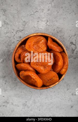 Getrocknete Aprikosen in einer Holzschale auf betonierter Oberfläche Stockfoto