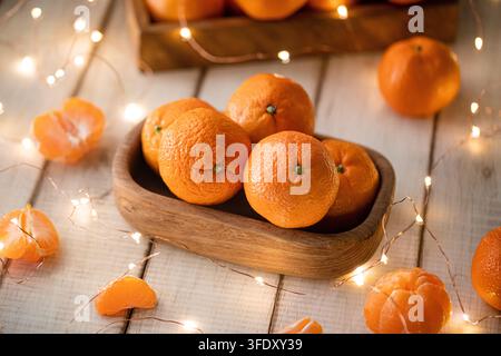 Reife Mandarinen in einer Holzschale mit Lichterkette Stockfoto