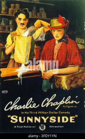 Vintage-Poster für Sunnyside (1919), die Stummfilmkomödie, die Charlie Chaplin für First National geschrieben, inszeniert und gespielt hat. Die Kunst zeigt Chaplin hinter einer Ladentheke, wie er lächelnd eine überlaufende Milchflasche neben einer Frau in rotem Schal und gefiedertem Hut hält, umgeben von Regalen mit Gläsern und Waren. Der handgemalte Stil und die lebhafte Komposition fangen den Humor, die Farbe und die Werbeeleganz des frühen zwanzigsten Jahrhunderts ein. Stockfoto