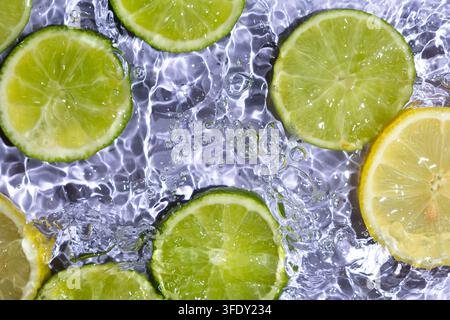 Frische Zitrusfrucht-Scheiben, die im Wasser spritzen, als Hintergrund Stockfoto