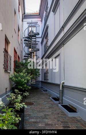 Topfpflanzen mildern den ruhigen Durchgang zwischen restaurierten Wohnhäusern. Stockfoto