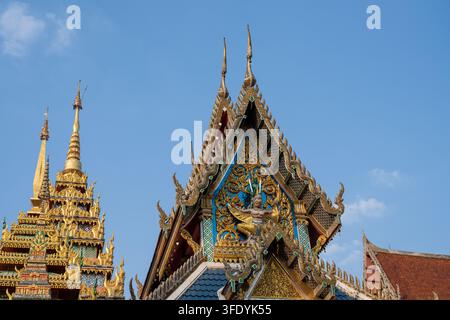 BANGKOK, THAILAND — 26. JANUAR 2026: Vergoldetes Ornament und eine gestaltete Gottheit füllen das Dachgiebel eines Tempogebäudes am Wat Khun Chan. Stockfoto
