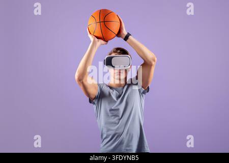 Junger muskulöser Typ spielt Basketball mit VR-Headset. Violetter Hintergrund Stockfoto