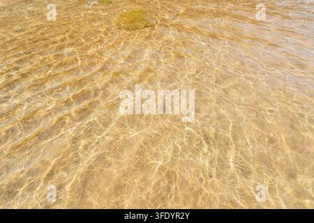 Sanfte, klare Meereswellen spülen sanft über sandigen Meeresboden in flachem türkisfarbenem Wasser an einem sonnigen Tag. Hotel Acapulco. Nordzypern Stockfoto