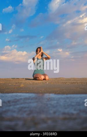 Strandszene mit Yoga, einer jungen Frau, Vajrasana, Donnerschlag-Pose, einer Frau und kniend Stockfoto