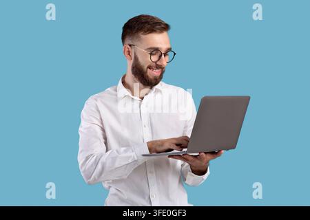 Erfolgreiche junge Kerl in formelle tragen mit Laptop-Computer über Blauer Studiohintergrund Stockfoto