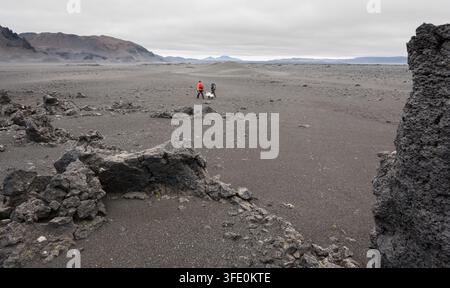 Teilnehmer der Artemis-Geologie-Feldtrainingsexpedition schieben einen Werkzeugwagen über eine vulkanische Landschaft in Island, die als Ersatz für lunare und planetare Prozesse dient, um Oberflächenwissenschaftsoperationen zu simulieren. Stockfoto