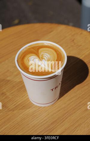 Seitenansicht von heißem Latte-Kaffee mit Herz-Latte-Art in einer weißen Keramiktasse mit Untertasse, isoliert auf weißem Hintergrund Stockfoto